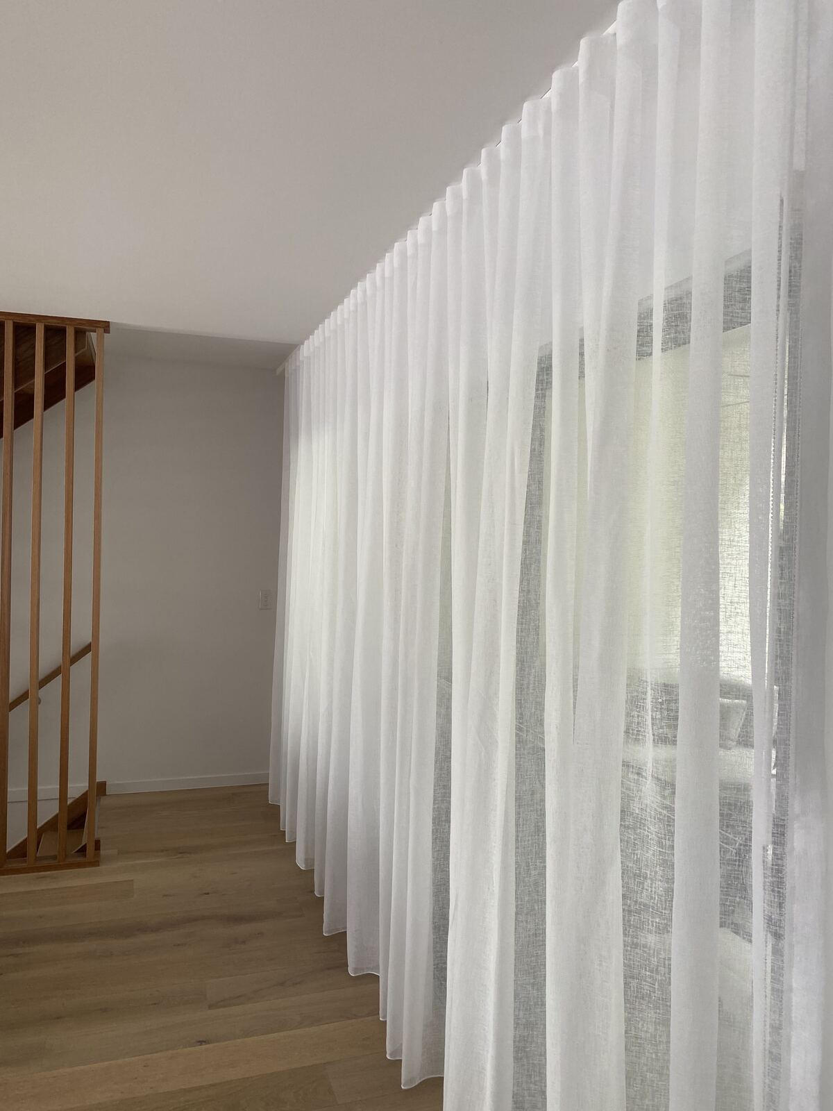 White sheer curtains beside a timber staircase