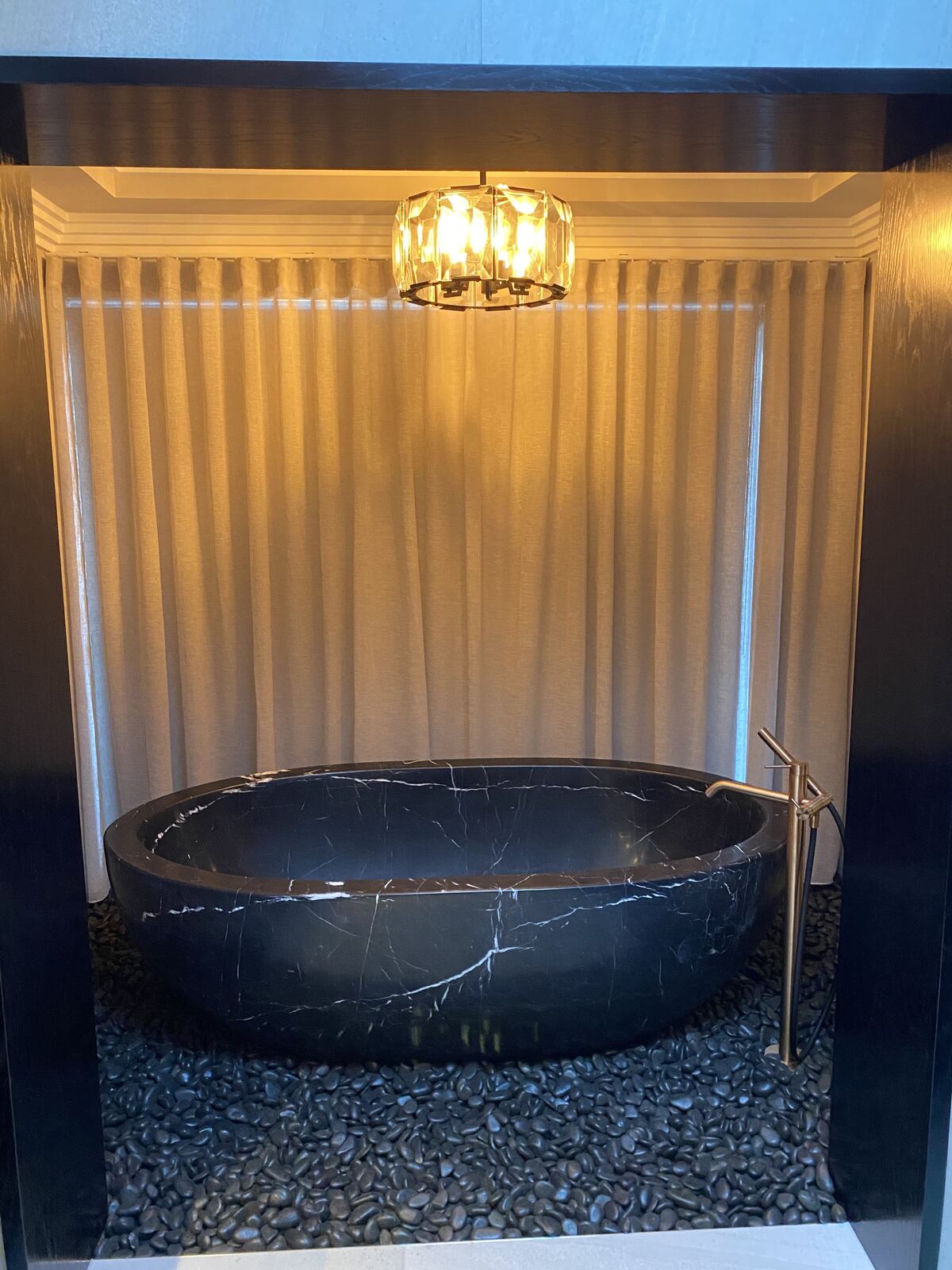 Sheer curtains framing a feature bath in a luxury ensuite
